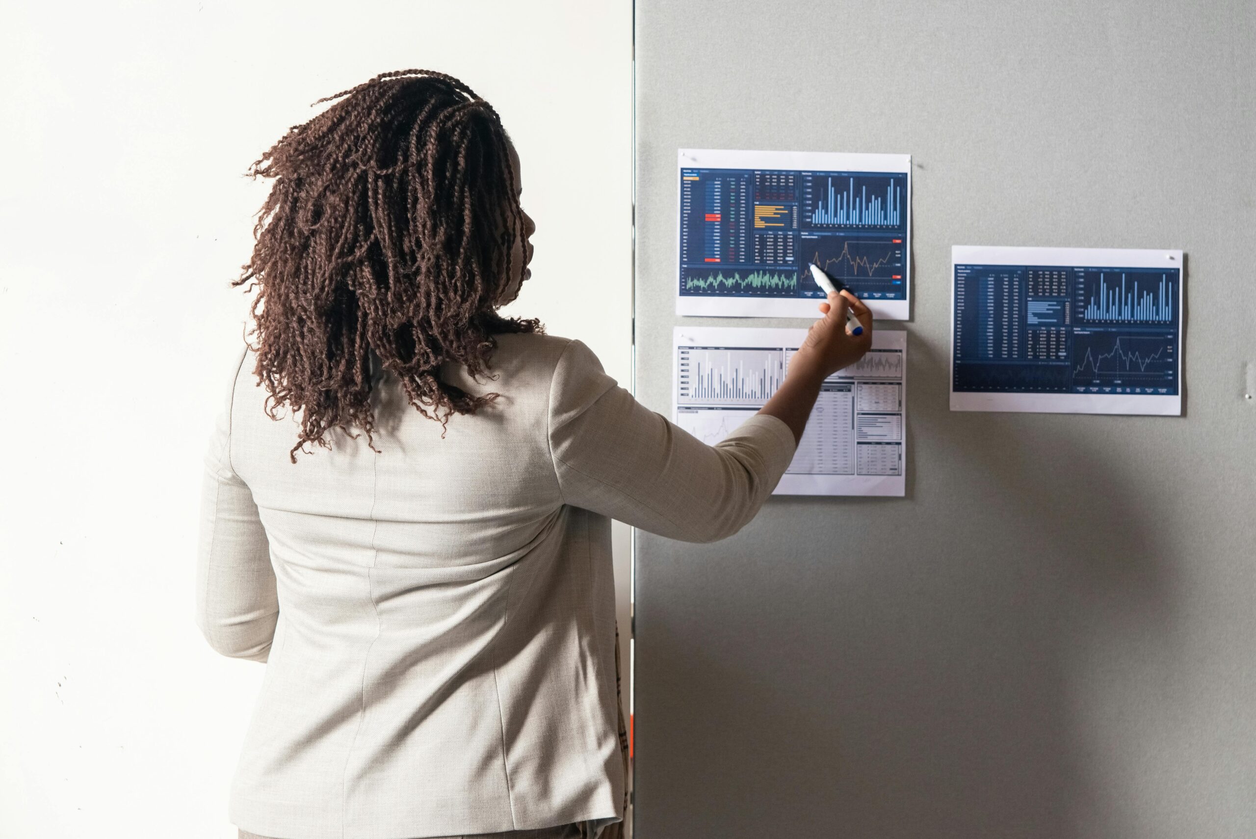 A businesswoman in a suit presenting financial data on charts during a meeting.